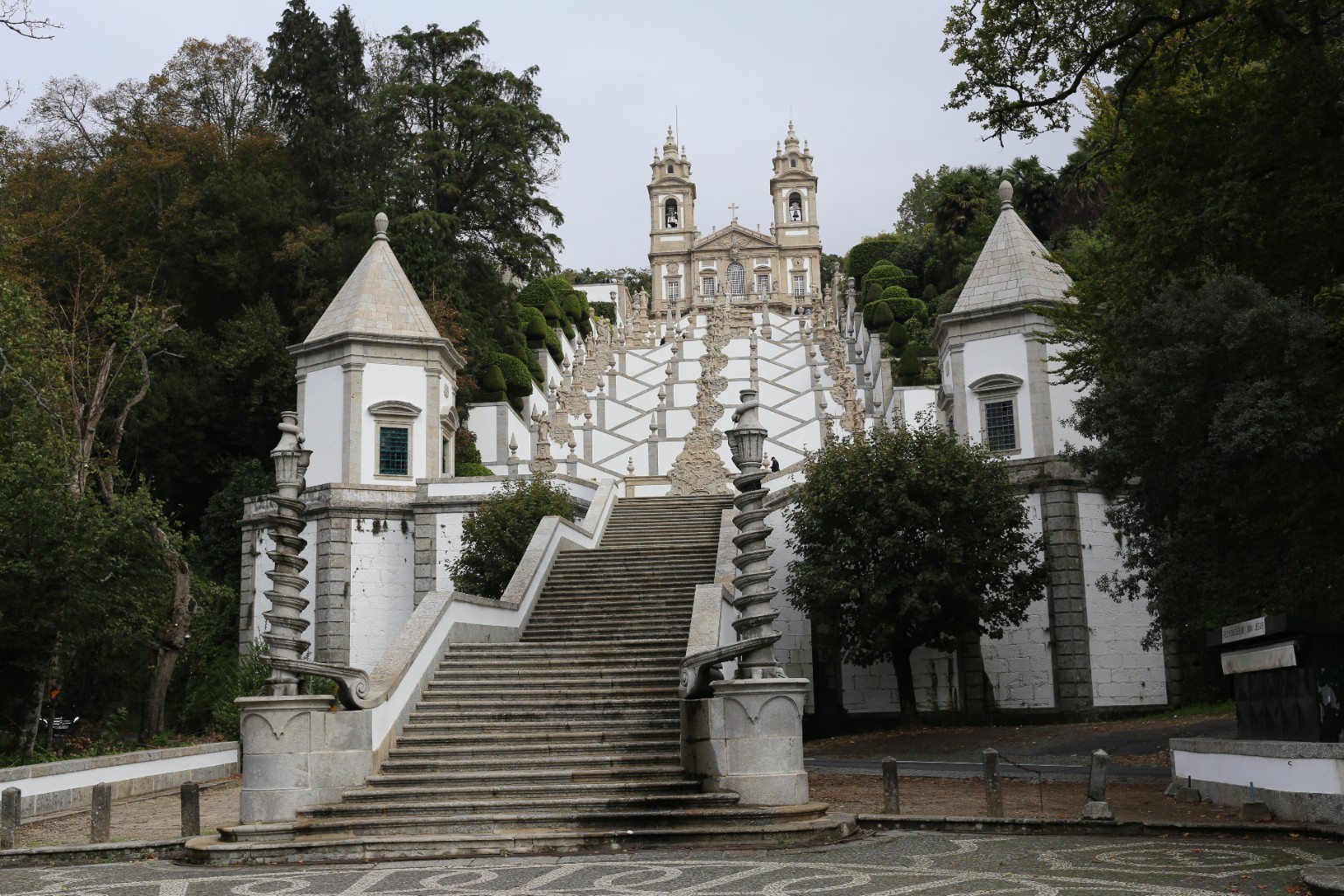 Granite steps and zigzagging white walls climb between chapels, sculpted fountains and clipped trees toward the twin towers of Bom Jesus do Monte in Braga, Portugal.