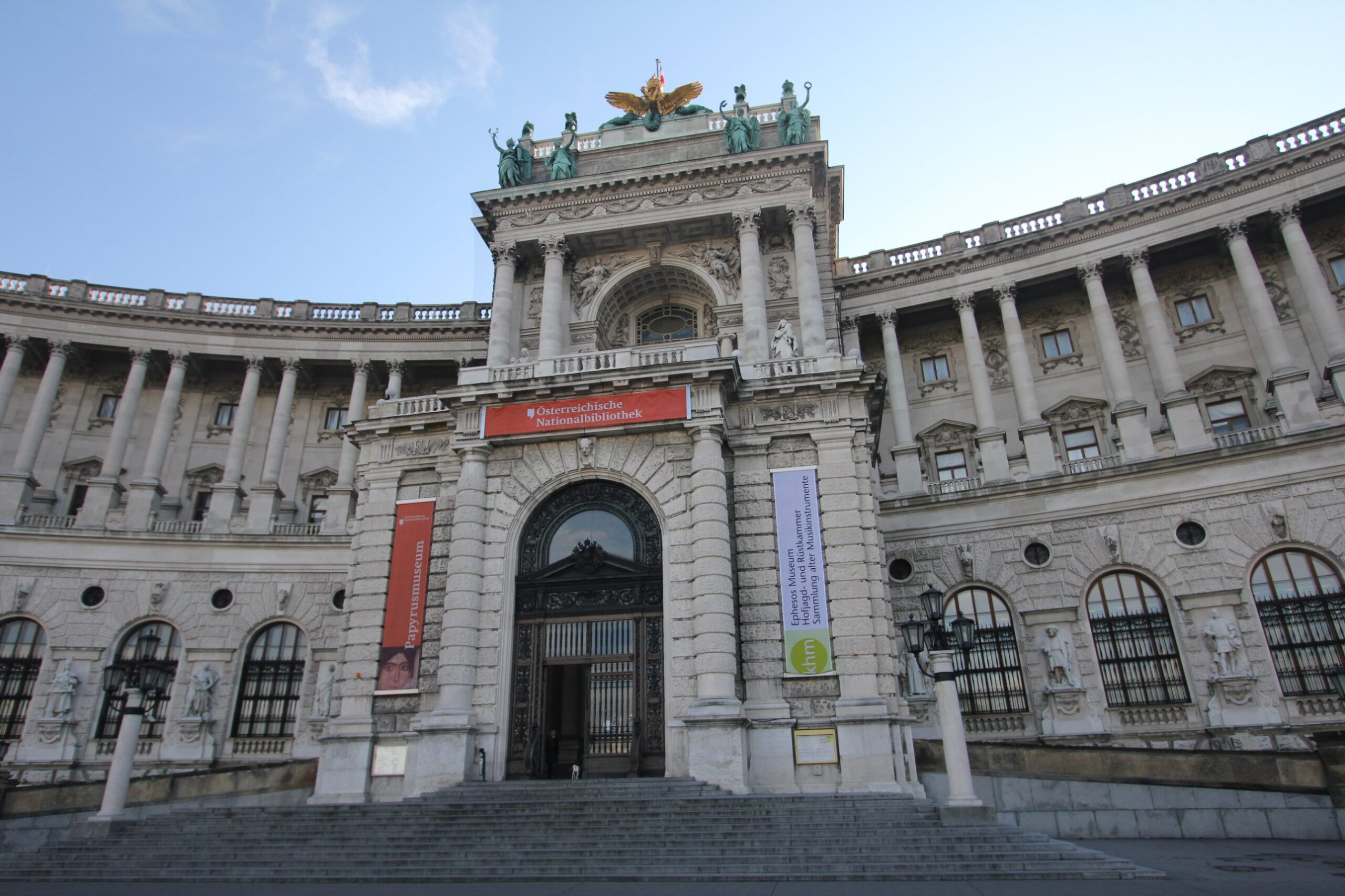 The main entrance of the Neue Burg on Heldenplatz in Vienna, with banners for the Austrian National Library, the Papyrus Museum, the Ephesos Museum, the Imperial Armoury and the Collection of Historic Musical Instruments