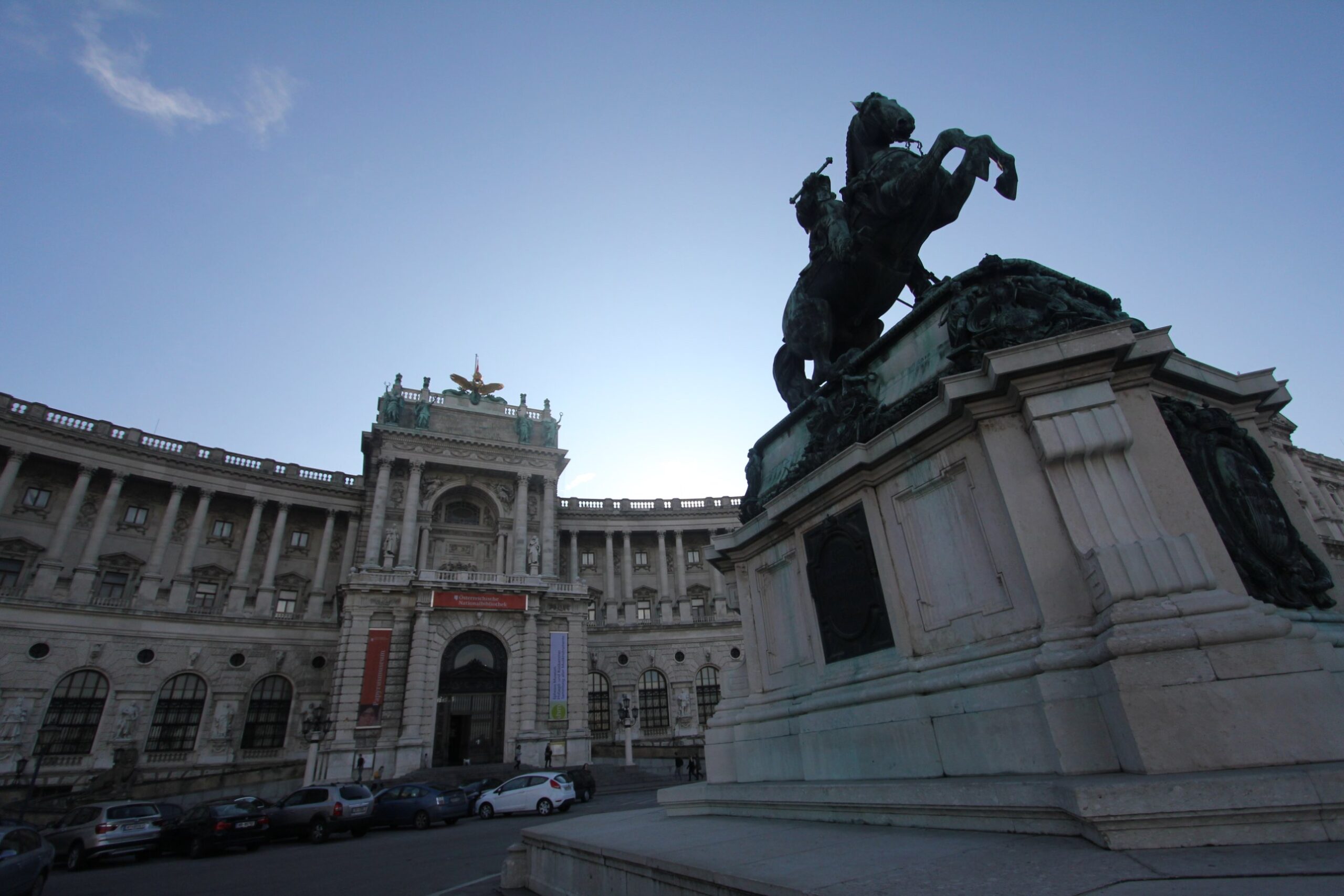 The bronze equestrian statue of Prince Eugene of Savoy on a rearing horse against the sky, beside the curved front of the Neue Burg on Heldenplatz in Vienna