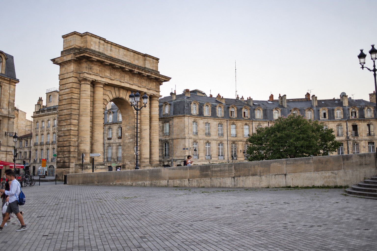 Porte de Bourgogne stone arch and limestone buildings with mansard roofs on Place Bir-Hakeim in Bordeaux.