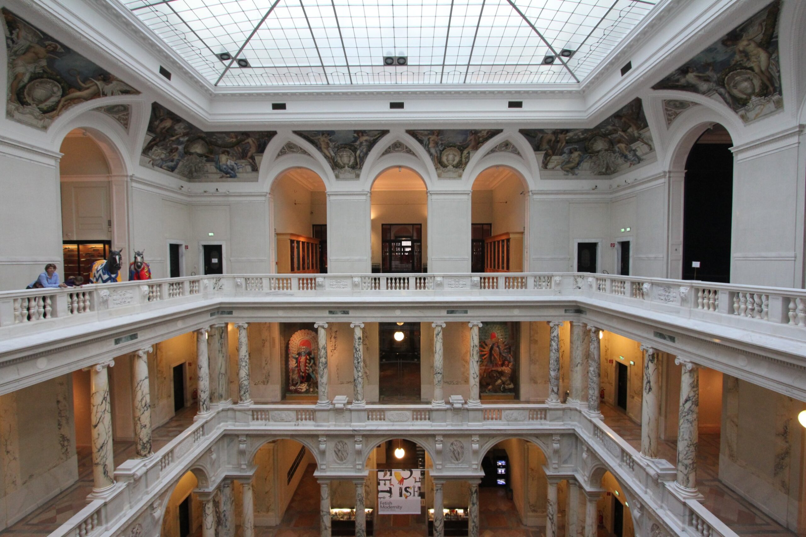 The glass-roofed atrium of the Weltmuseum Wien in the Neue Burg, with marble columns, balustraded galleries and painted lunettes